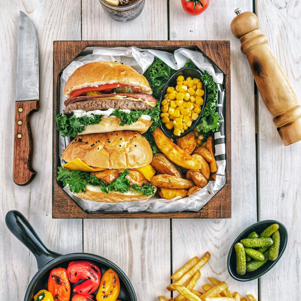 A mouth-watering gourmet burger meal with fries, peppers, and corn, perfect for a delicious dining experience.